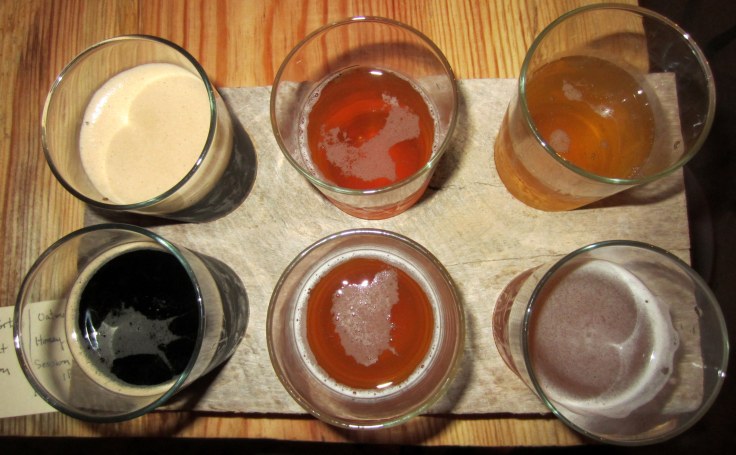 Sampler tray, clockwise from upper left: Corn Cob Smoked Porter, Thresher Coffee Saison, Cantilever Honey Melon Blonde, Spade Session IPA, Spoon Oatmeal Pale, and Cherry Stout.
